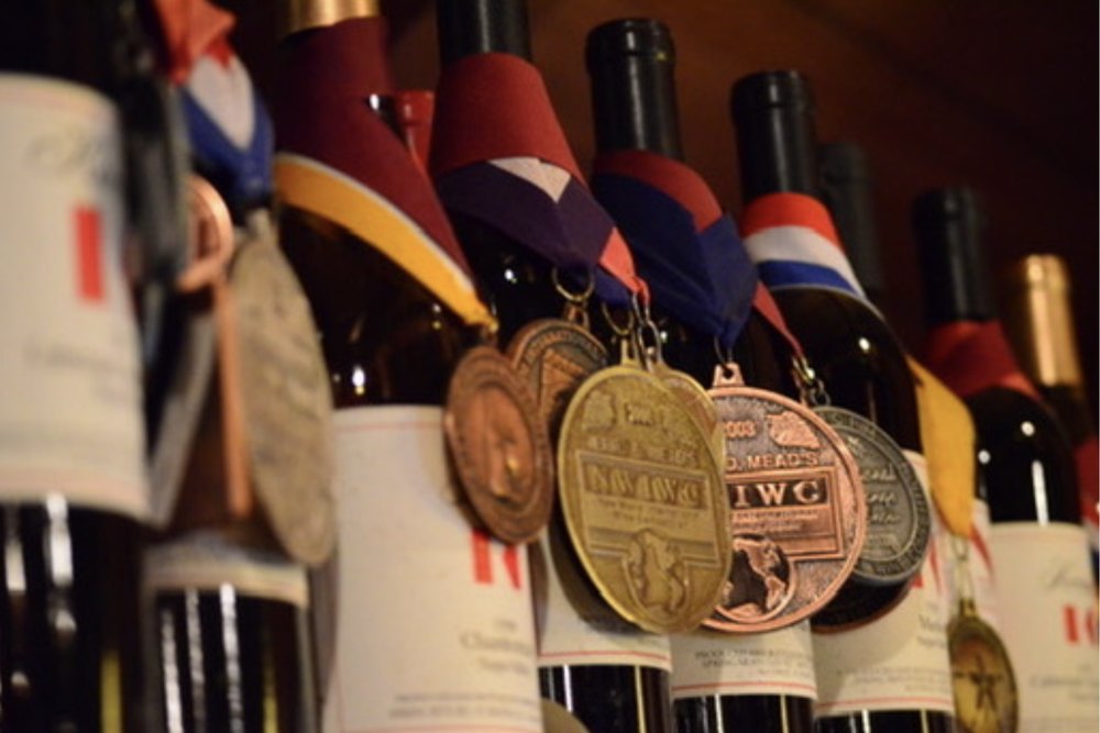 A row of Keenan bottles with competition medals hung on ribbons around their necks