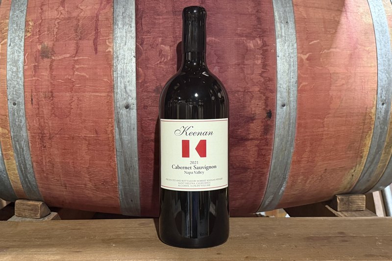 The Keenan Big Bottle Club shipment against a barrel — a single three-liter Jeroboam of Keenan Cabernet Sauvignon