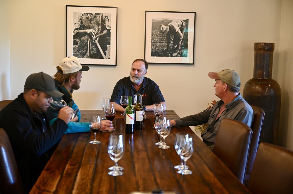 The Keenan blending team tasting through wines around the long wooden table in the tasting room, two Keenan bottles and rows of glasses in front of them
