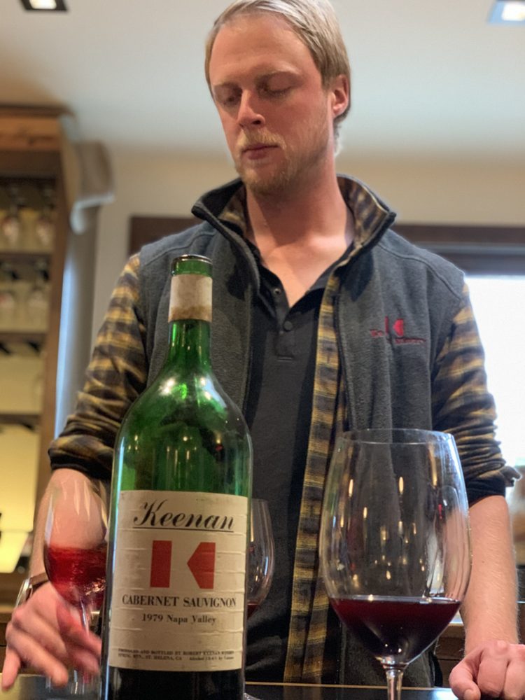 Reilly Keenan behind the bar with an old Keenan Cabernet Sauvignon and two poured glasses