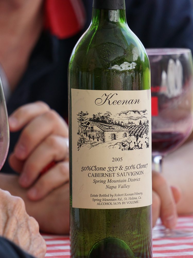 An older-vintage Keenan Cabernet Sauvignon from the Spring Mountain District open on a table, two glasses of red poured beside it