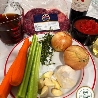 The ingredients laid out: Wagyu shank, carrots, celery, thyme, onions, garlic, diced tomatoes, stock and a bottle of Keenan 2022 Cabernet Franc
