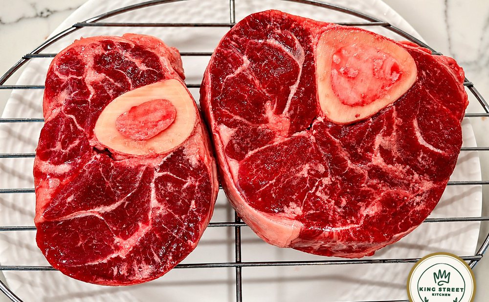 Two cross-cut Vermont Wagyu beef shanks on a wire rack, showing marbling, seams of connective tissue and the marrow bone