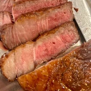 Slices of Wagyu rib eye showing an even rose interior, with pan sauce