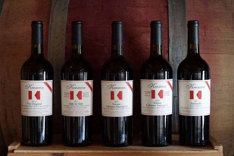 Five Keenan secret-cellar bottles standing against a barrel