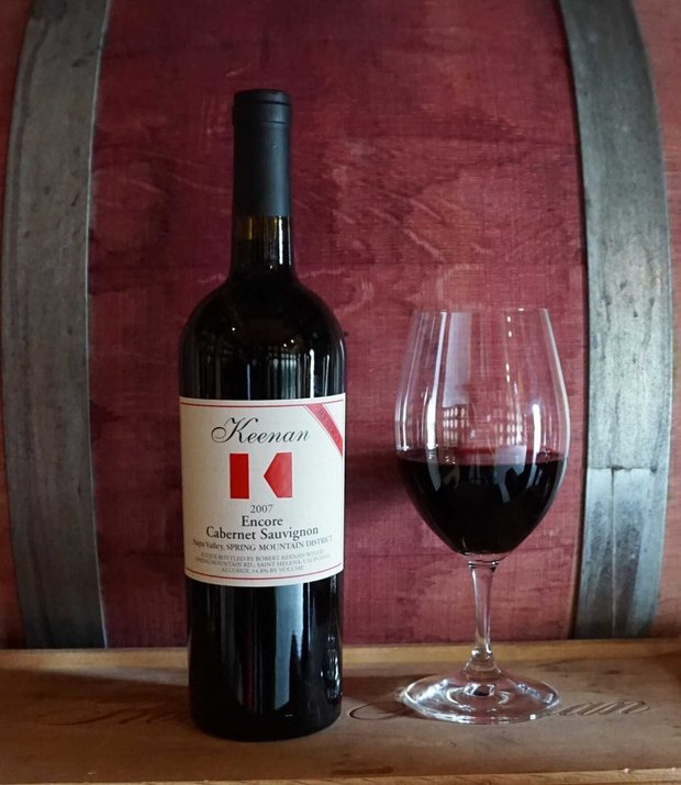 Bottle of Keenan ‘Encore’ secret Cabernet Sauvignon with a poured glass, against the barrel room