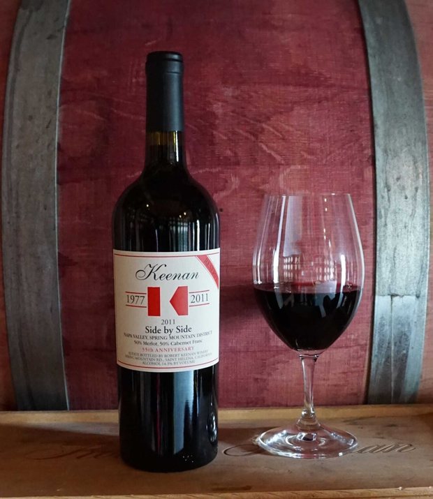Bottle of Keenan ‘Side by Side’ secret wine with a poured glass, against the barrel room