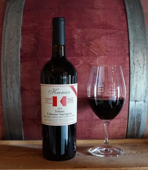 Bottle of Keenan ‘Tribute’ secret Cabernet Sauvignon with a poured glass, against the barrel room