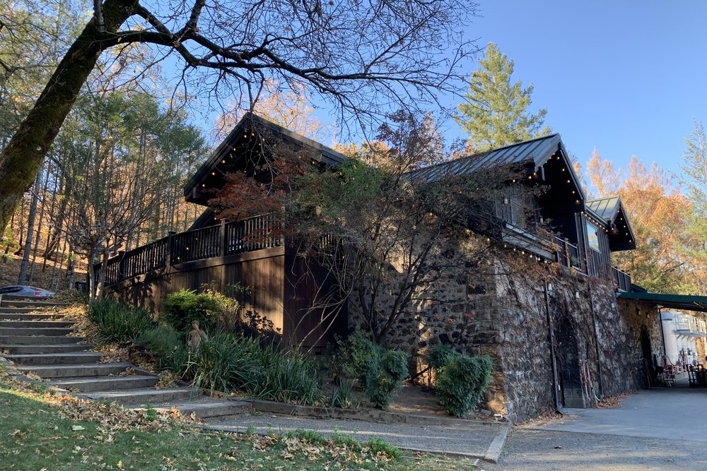 The stone winery building at Keenan, its timber balcony strung with lights, autumn trees rising behind it