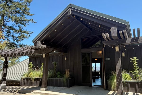 The Keenan Winery tasting room entrance, a timber pergola strung with lights above dark board-and-batten walls and planted borders