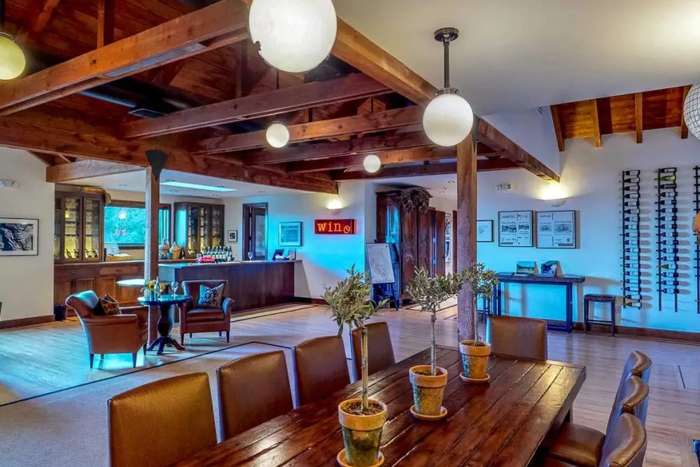 The Keenan tasting room, with open timber beams, pendant lights, a long table and the bar beyond