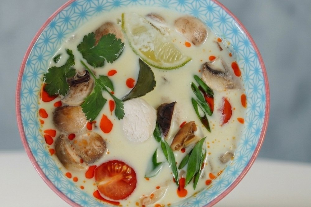 A bowl of Thai coconut soup with mushrooms, chicken, lime, coriander and chilli oil