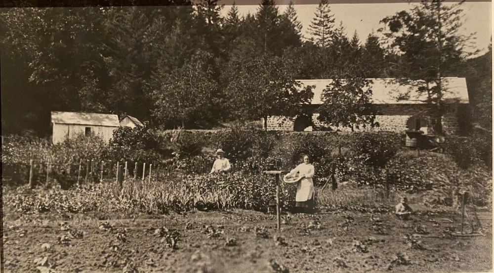 The Peter Conradi winery on Spring Mountain in 1910, its stone building and outbuilding standing above a planted garden where two women are working &mdash; the site Robert Keenan bought in 1974 and where the Keenan Chardonnay vineyard grows today