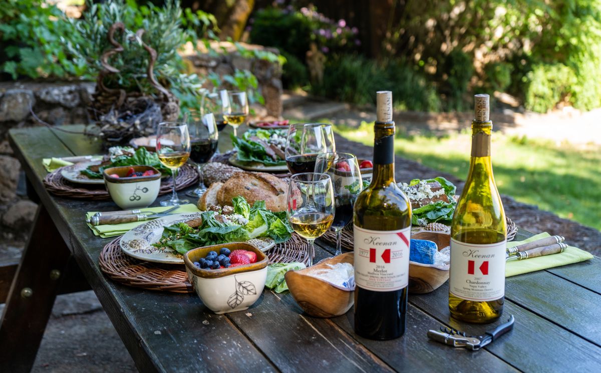 Picnic table set with Keenan wine, cheese, and fruit overlooking the Spring Mountain vineyards