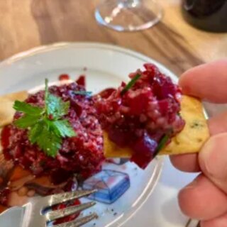 The finished tartare moulded on the plate with pomegranate syrup and parsley