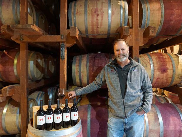 Michael Keenan in the Keenan Winery barrel room with a row of Keenan bottles