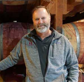 michael-keenan-standing-in-front-of-wine-barrels
